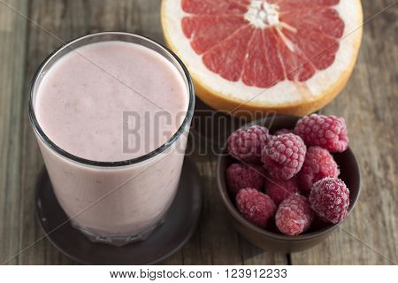 Smoothies with frozen raspberries and grapefruit with yogurt on a wooden table.