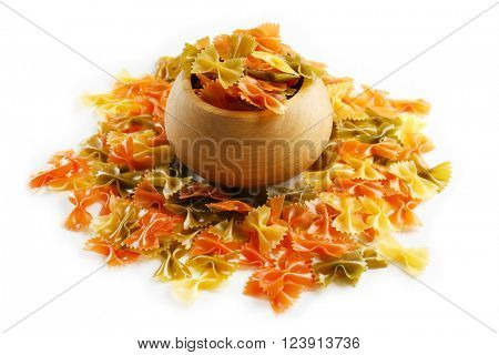 Colorful bow pasta in wooden pot on white background, close up