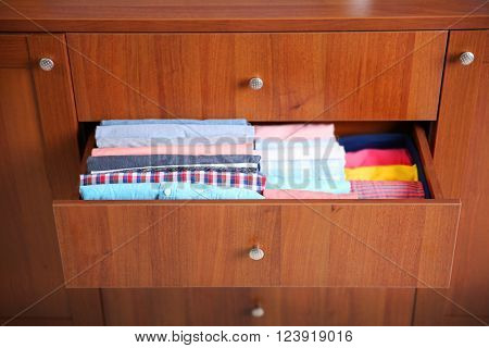 Neatly folded clothes in wooden drawer