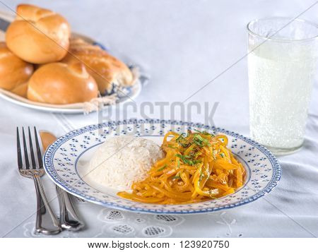 Olluquitos con charqui, a typical Peruvian potato dish with dried Alpaca meat served in white and blue dish in white table setting