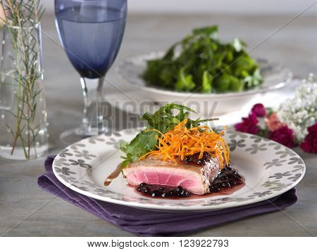 Tuna steak with berry flavored sauce served in fine dining setting