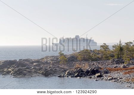 GRISSLEHAMN SWEDEN - MAR 28 2016: Large ferry partly hidden in fog cliffs and trees a sunny day during spring time in scandinavia in Grisslehamn Mars 28 2016 Grisslehamn Sweden