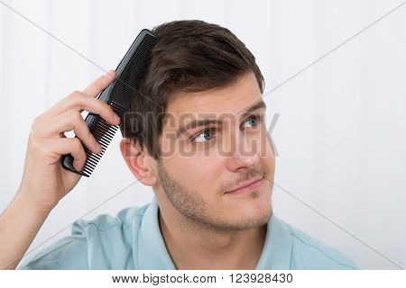 Close-up Of Young Man Combing His Hair With Comb