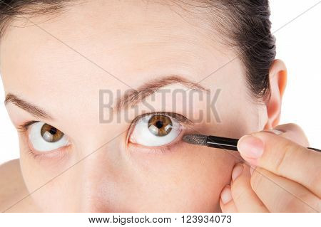 Young girl is doing her makeup isolated on white