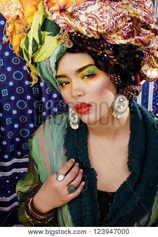 beauty bright woman with creative bright make up, many shawls on head like cubian, ethno look closeup