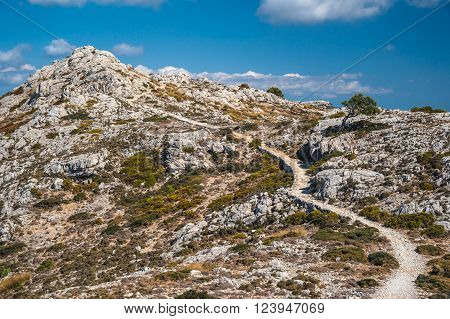 Beautiful landscape with a lane between rocky mountains on the western part of Mallorca island, Spain.  Tramuntana mountains with green bushes. Tourist trekking destination in Spain.