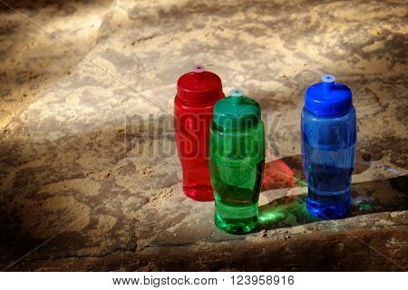 Detailed red, green, and blue bottles on rought rocks