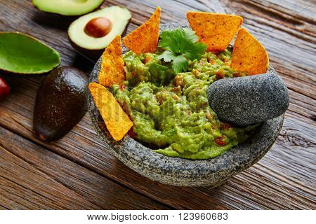 Guacamole with nachos avocado in Mexican molcajete in aged wood table