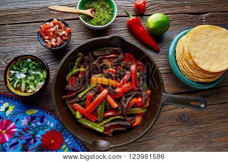 Beef fajitas in a pan with sauces chili and sides Mexican food