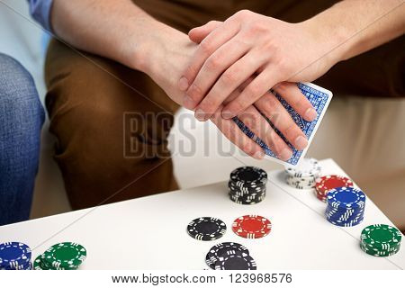 leisure, games, friendship, gambling and entertainment - close up of male hand with playing cards and chips at home