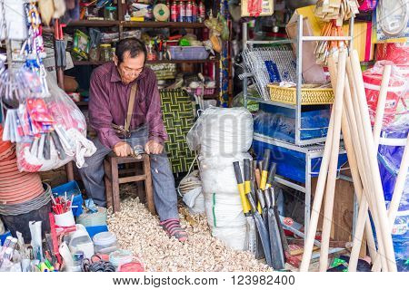 Siem Reap, Cambodia, 15 Nov 2015: Store Keeper At Work Shredding And Refining Wooden Poles For Sale.