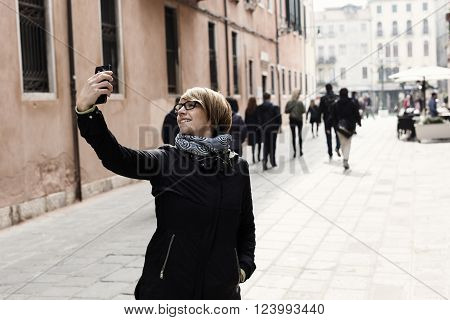 Traveling around the world. Beautiful modern woman making selfie. Local sights in the background.