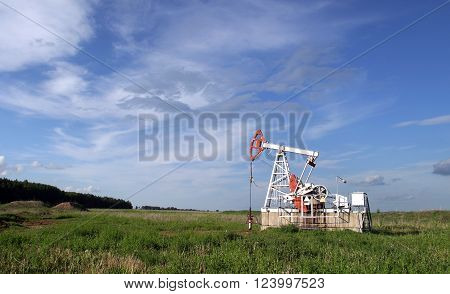 Oil pump in the field on a background cloudy sky in summer