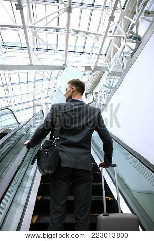 Businessman at the airport going down the escalator