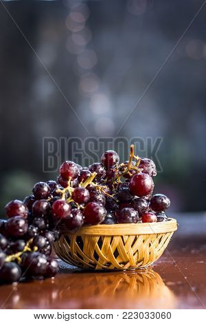 Close Up Of Grapes,vitis Vinifera In A Basket On A Brown Wooden Surface.