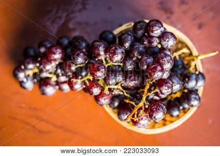 Close Up Of Grapes,vitis Vinifera In A Basket On A Brown Wooden Surface.