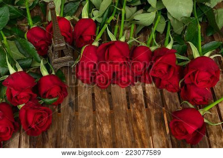 red fresh roses with eiffel tower on wooden table