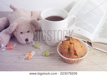 Leisure. A cup of coffee, a cupcake and a book on the table. toning