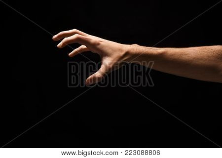 Taking. Male hand grab some item on black isolated background, cutout, copy space
