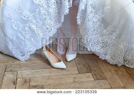 the bride wears white shoes on foot in the wedding day. close-up shoot