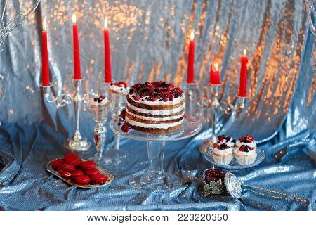 Sweet bar with muffins cakes, sweets, fruits and candle holders in area of wedding party on a silver background.
