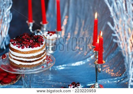 Sweet bar with muffins cakes, sweets, fruits and candle holders in area of wedding party on a silver background.