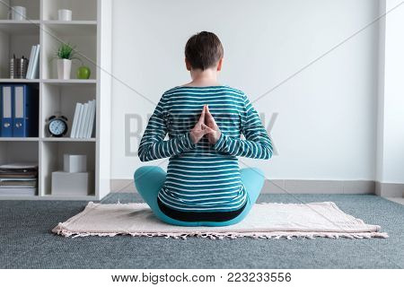 Pregnant woman practicing yoga exercise at home. Pregnancy yoga and indoors fitness concept. Ungraded low contrast footage with natural window light.
