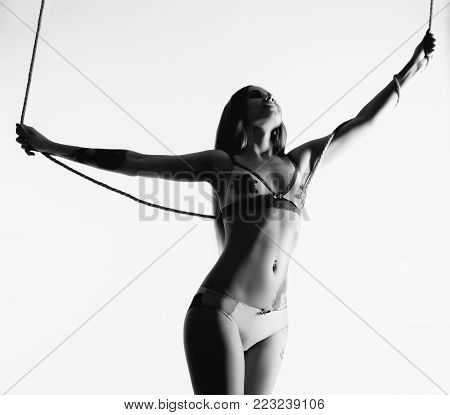 Perfect slim girl with a rope posing on a light background. Sexy athletic body