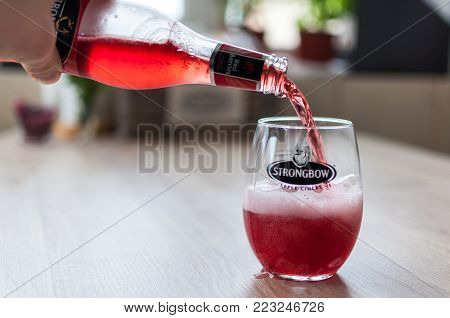 TIMISOARA, ROMANIA - JANUARY 04, 2018: Strongbow bottle and glass on a wooden table. Apple cider. Red berries.