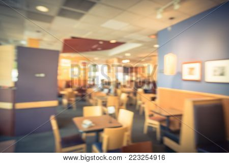 Blur abstract interior of counter-serve bakery, cafe chain shop in USA. Wooden table chair in compact design, natural light from windows. Customer enjoy sandwiches, salads, bread, coffee. Vintage tone