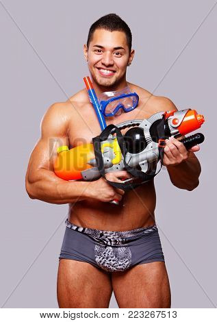 muscular man with water gun and with swimming equipments