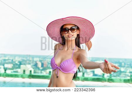 Swimsuit Concept. Beautiful girl wearing pink swimsuit. Beautiful girl in swimwear is relaxing at the swimming pool. Independent living sexy woman at the city center pool.