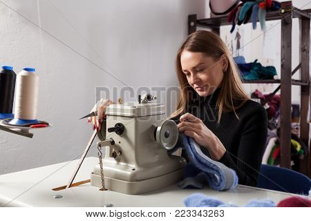 Young woman skinner sewing fur coat. Furrier at the factory in the neck fur coat