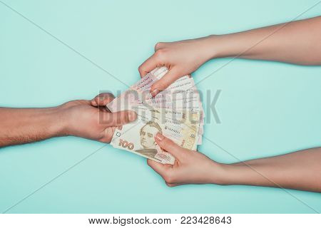 cropped shot of woman taking cash from man isolated on turquoise