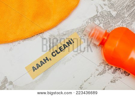 Ready for cleanup.Set of orange cleaning tools: rags, sponges, dishwashing liquid on a light concrete background. Printed Aaah, Clean inscription, flat lay, top view