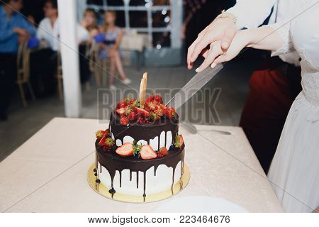 Bride and groom cut wedding cake with fresh flowers rose with knife. Coup