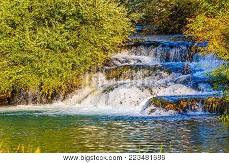 Cascade waterfalls are lit by sunset. Charming tourist town on the Korana river. Croatia, Slunj. Concept of ecological and photo tourism