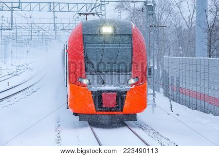 Highspeed train approaches to the station platform at snowstormy day time.