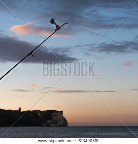 fhishing rod with a bell at sunrise