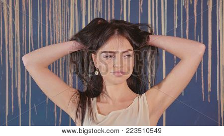 Portrait of a beautiful cheerful young woman smiling over colorful wall. Girl is playfully corrects hair.