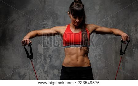 Athletic woman in sportswear doing exercises with expander