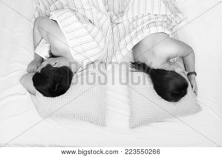 couple man and woman lying in bed under a blanket with his back turned to each other