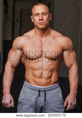 Strong muscular man bodybuilder poses and shows his muscles