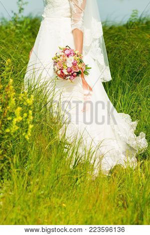 Bride in a white dress on thepark with a wedding bouquet in hands