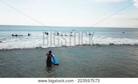 Surfing girl on surfboard on sunrise in the ocean. People ride good wave. Modern active sport lifestyle and summer vacation. People riding boards on the waves.
