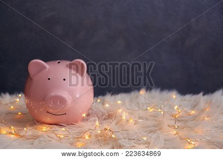 Piggy bank and Christmas garland on faux fur
