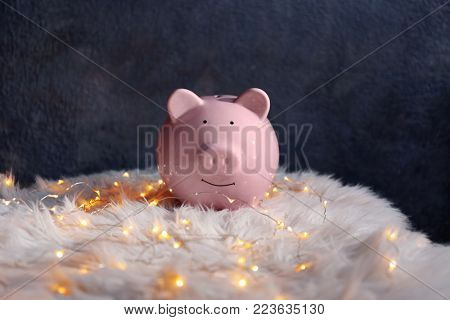 Piggy bank and Christmas garland on faux fur