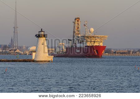 New Bedford, Massachusetts, USA - January 19, 2018: Geotechnical drill ship Fugro Explorer passing Palmer's Island lighthouse during early morning departure from New Bedford