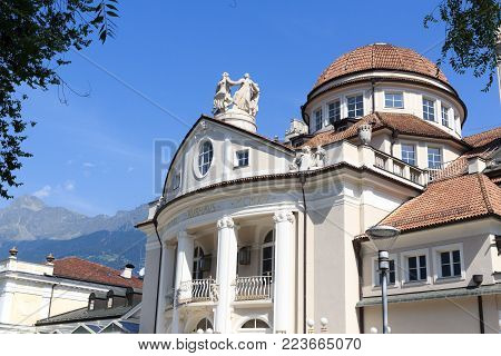 Merano, Italy - August 3, 2017: Kurhaus of Merano at promenade and mountain alps panorama in South Tyrol. The Kurhaus is a famous building in the town and a symbol of it. Text on the Building is 