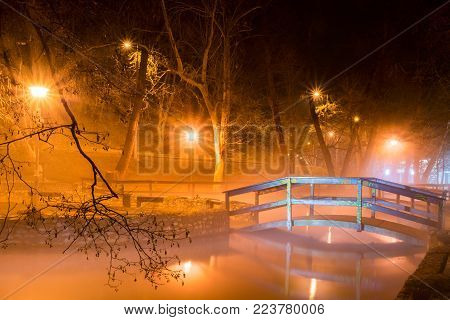 Beautiful night scene with a wooden bridge over the lake illuminated by lights in  Miskolctapolca town, Hungary